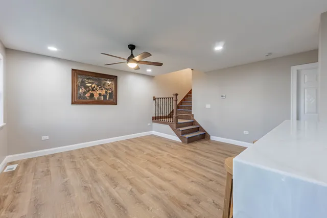 a view of an empty room with a chandelier fan and wooden floor