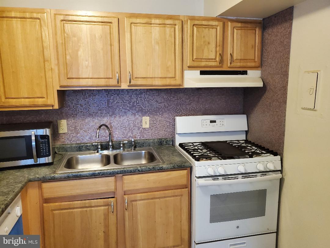 8481 Greenbelt Road, Unit T2 Greenbelt, MD 20770 - Photo 3 of 22 a kitchen with granite countertop a stove sink and cabinets