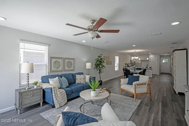 a living room with furniture a potted plant and a large window