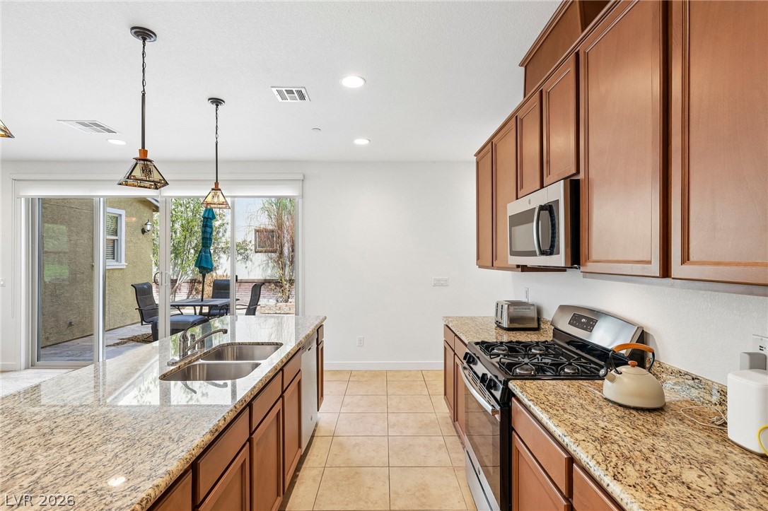 1100 East Sunset Road Henderson, NV 89011 - Photo 15 of 63 Rich wood cabinetry and expansive granite countertops frame this light-filled culinary workspace.