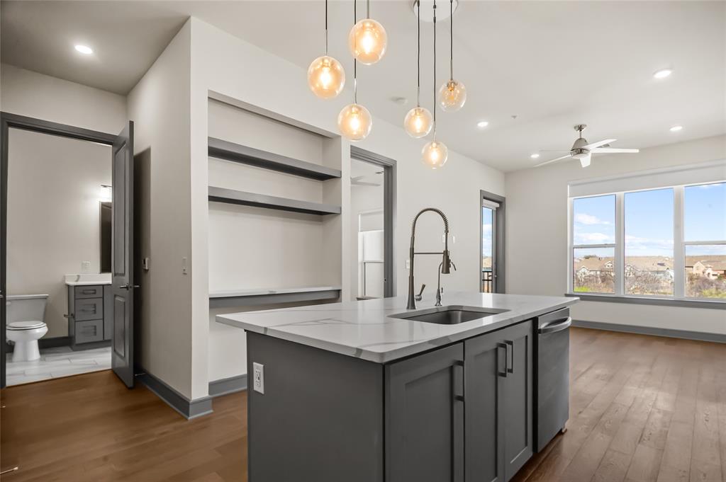 2700 Old Denton Road, Unit 3318 Carrollton, TX 75007 - Photo 2 of 24 Kitchen with open shelves, hanging light fixtures, an island with sink, and dark wood-style flooring