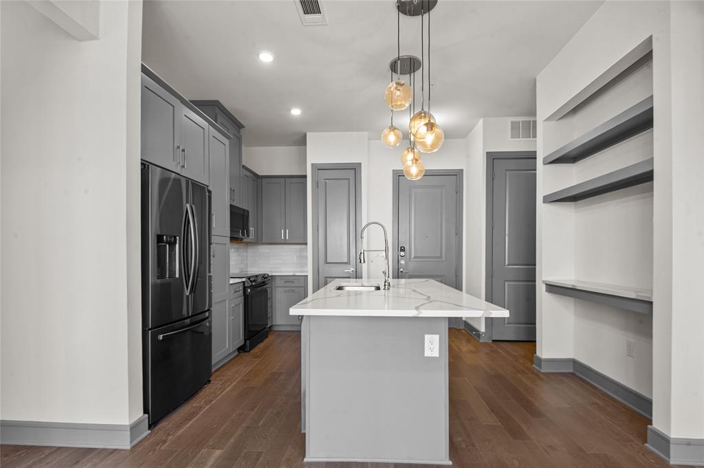 2700 Old Denton Road, Unit 3318 Carrollton, TX 75007 - Photo 8 of 24 Kitchen with gray cabinets, stainless steel fridge, decorative light fixtures, a kitchen island with sink, and open shelves