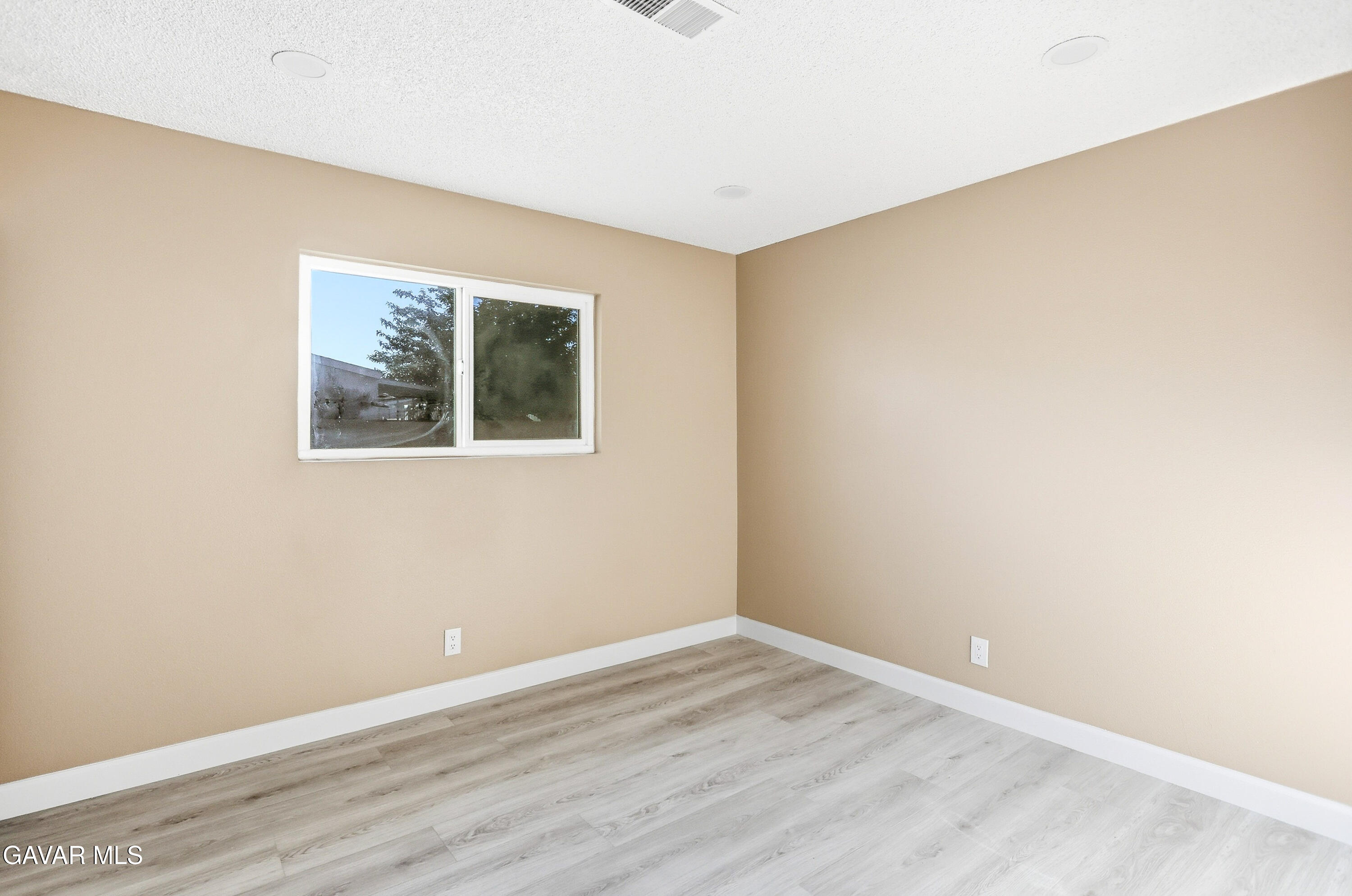 3340 West Roxbury Street Rosamond, CA 93560 - Photo 17 of 20 a view of an empty room with wooden floor and a window