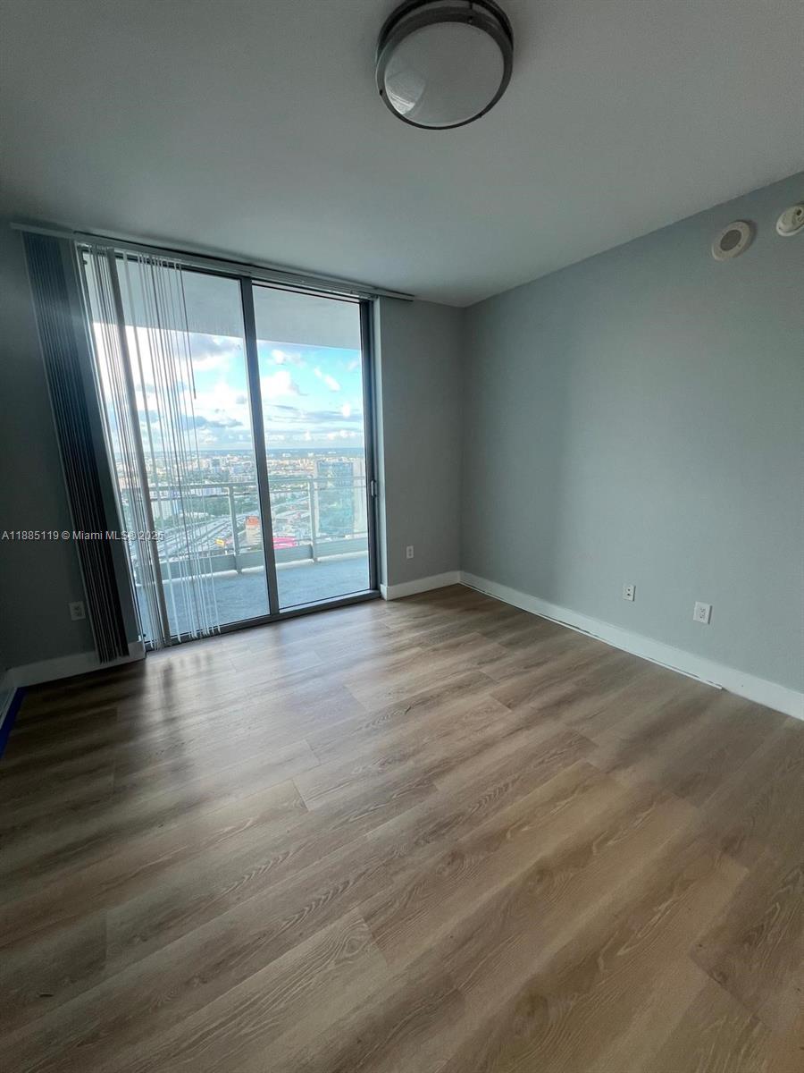 90 Southwest 3rd Street, Unit 4208 Miami, FL 33130 - Photo 2 of 17 an empty room with wooden floor and windows