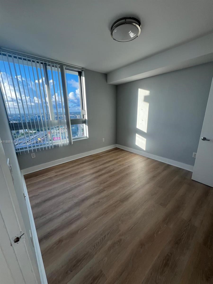90 Southwest 3rd Street, Unit 4208 Miami, FL 33130 - Photo 3 of 17 wooden floor in an empty room with a window