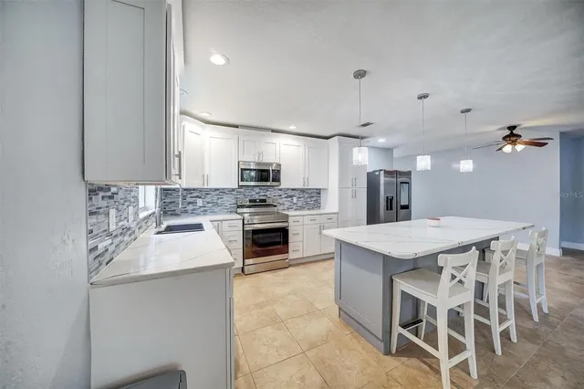 a kitchen with white cabinets appliances a sink and a window