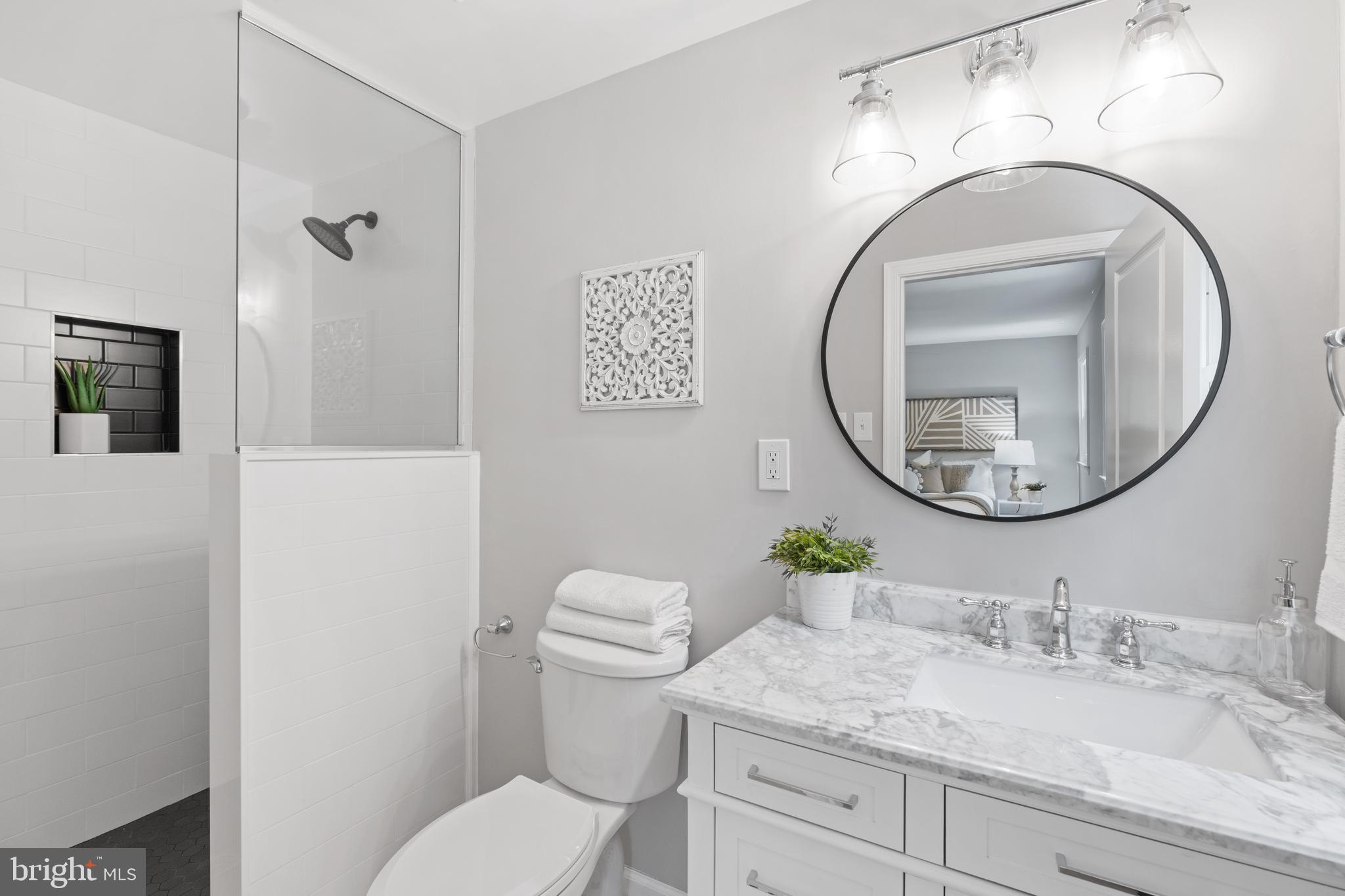 7003 Wardman Road Baltimore, MD 21212 - Photo 23 of 42 a bathroom with a granite countertop toilet a sink and a mirror