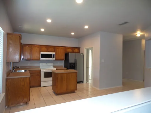 a kitchen with stainless steel appliances kitchen island granite countertop a refrigerator and a stove top oven