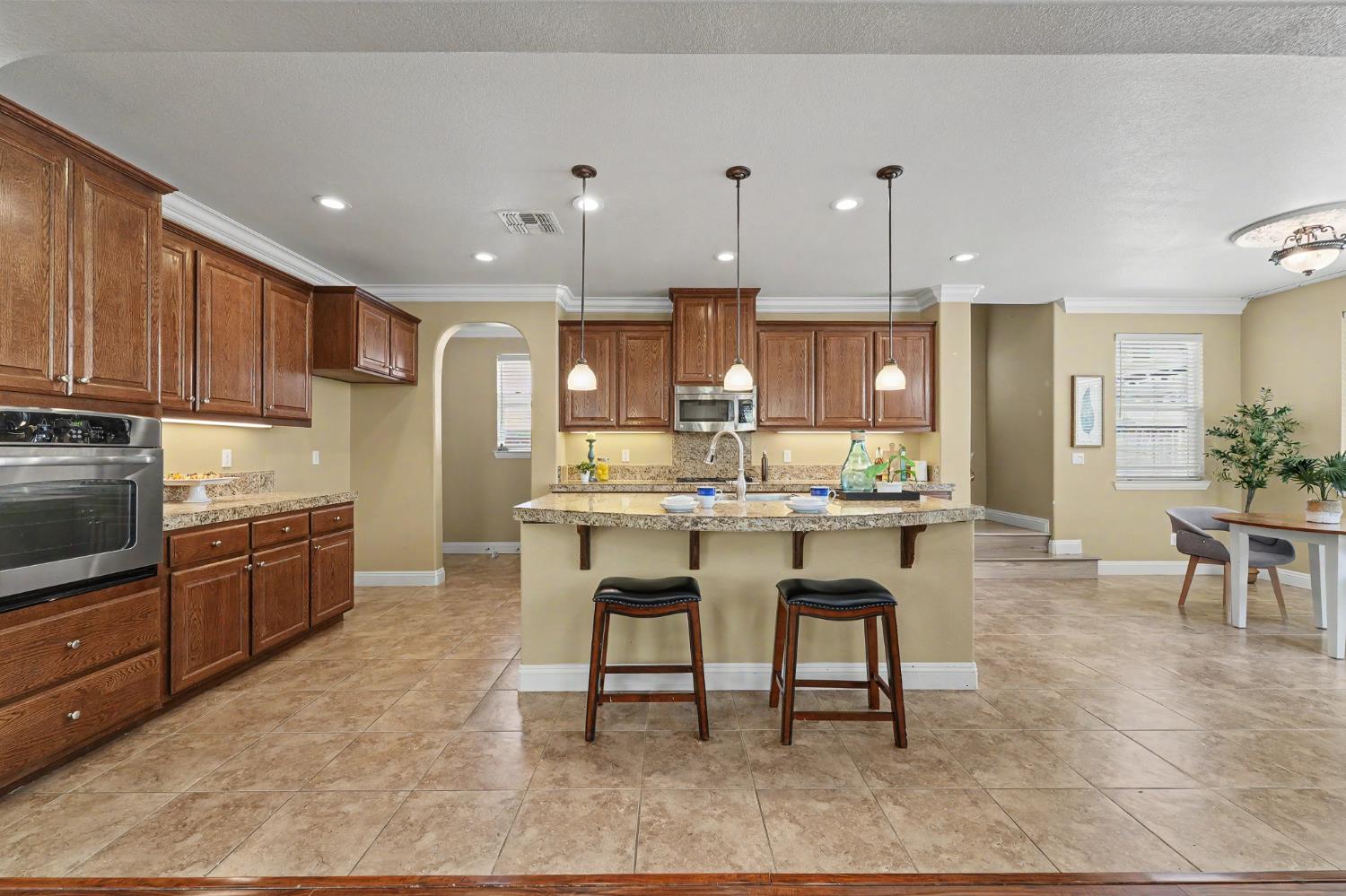 1223 East Springer Drive Turlock, CA 95382 - Photo 14 of 48 a kitchen with granite countertop a table chairs microwave and cabinets