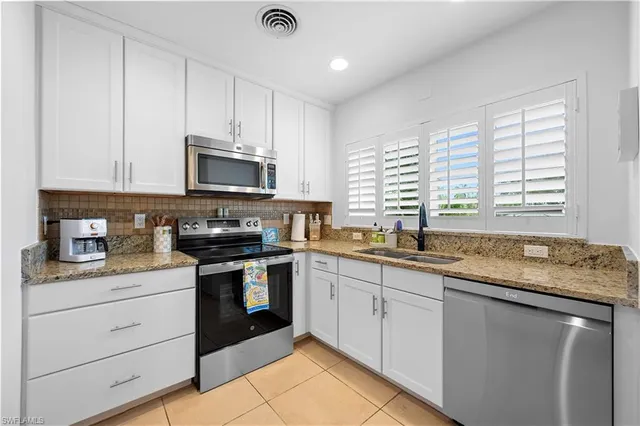 a kitchen with granite countertop stainless steel appliances white cabinets granite counter tops and a window