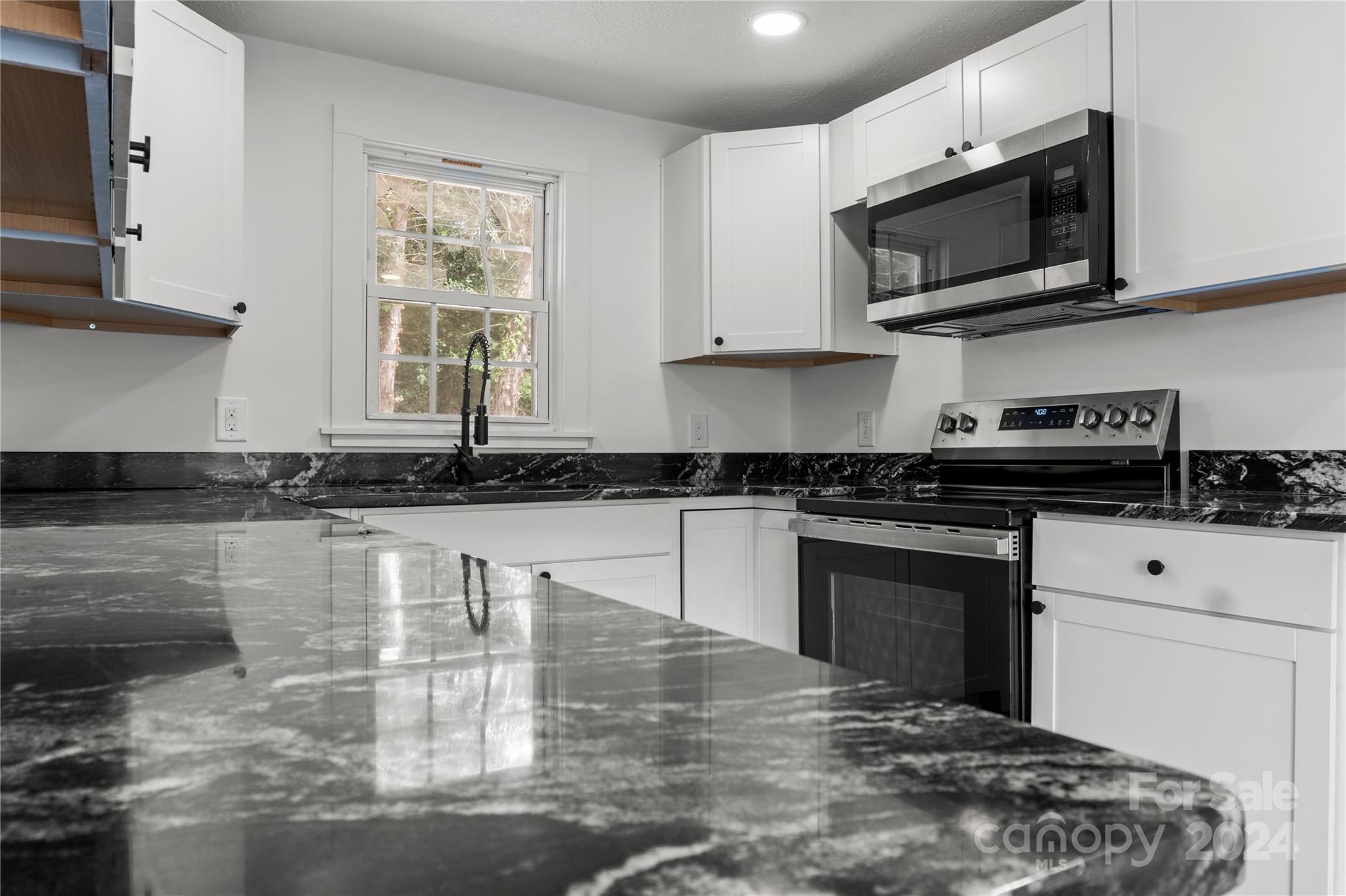 4879 Joe Powell Road Morganton, NC 28655 - Photo 15 of 35 a kitchen with stainless steel appliances granite countertop a stove a sink and a microwave