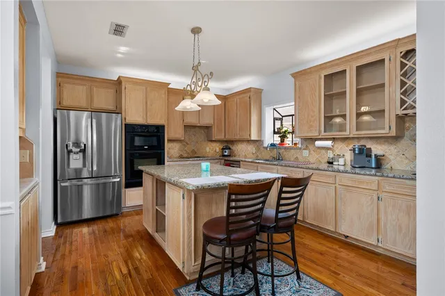 a kitchen with kitchen island granite countertop a sink a counter space stainless steel appliances and cabinets