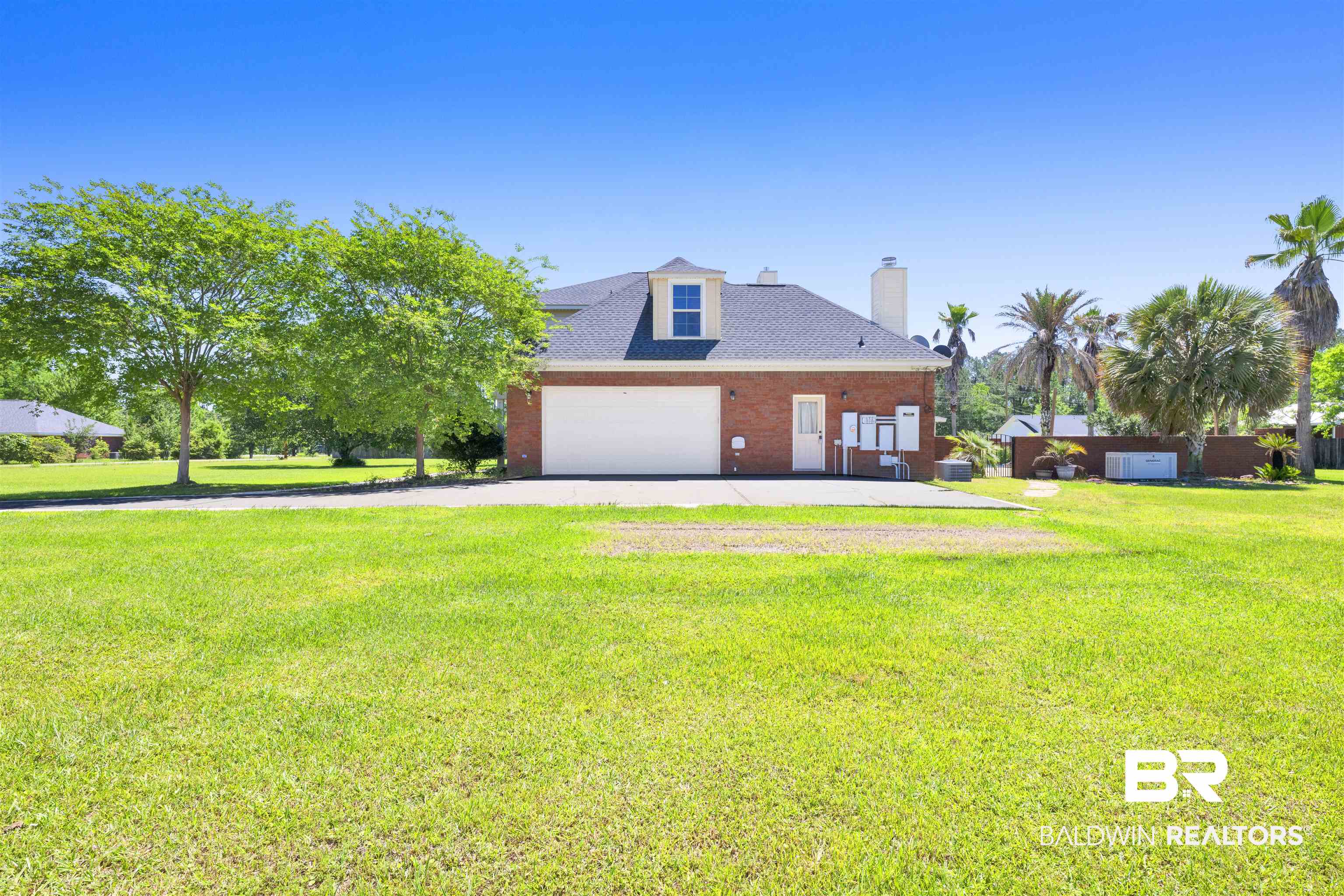 12944 Anna's Way Stapleton, AL 36578 - Photo 20 of 64 Brick exterior featuring a dormer window, an attached garage with a white door, a concrete pad, a white entry door, and a white chimney