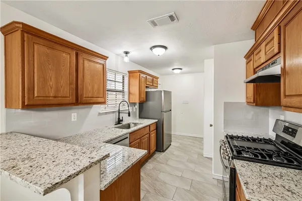 a kitchen with stainless steel appliances granite countertop a sink stove and refrigerator