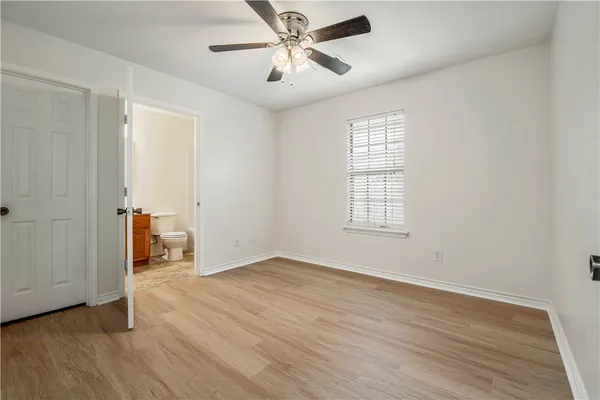 an empty room with wooden floor and ceiling fan