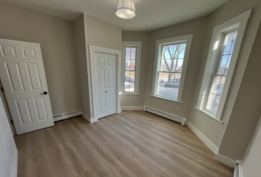 17 M Street Boston, MA 02127 - Photo 6 of 10 an empty room with wooden floor and windows