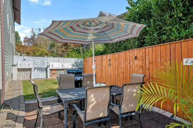 a view of a patio with table and chairs under an umbrella with a small yard
