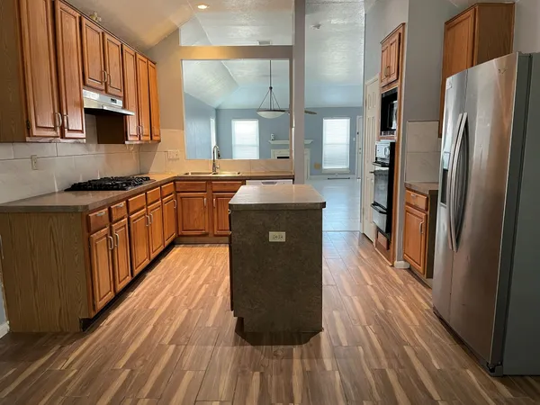 a kitchen with stainless steel appliances granite countertop a stove a sink and a refrigerator