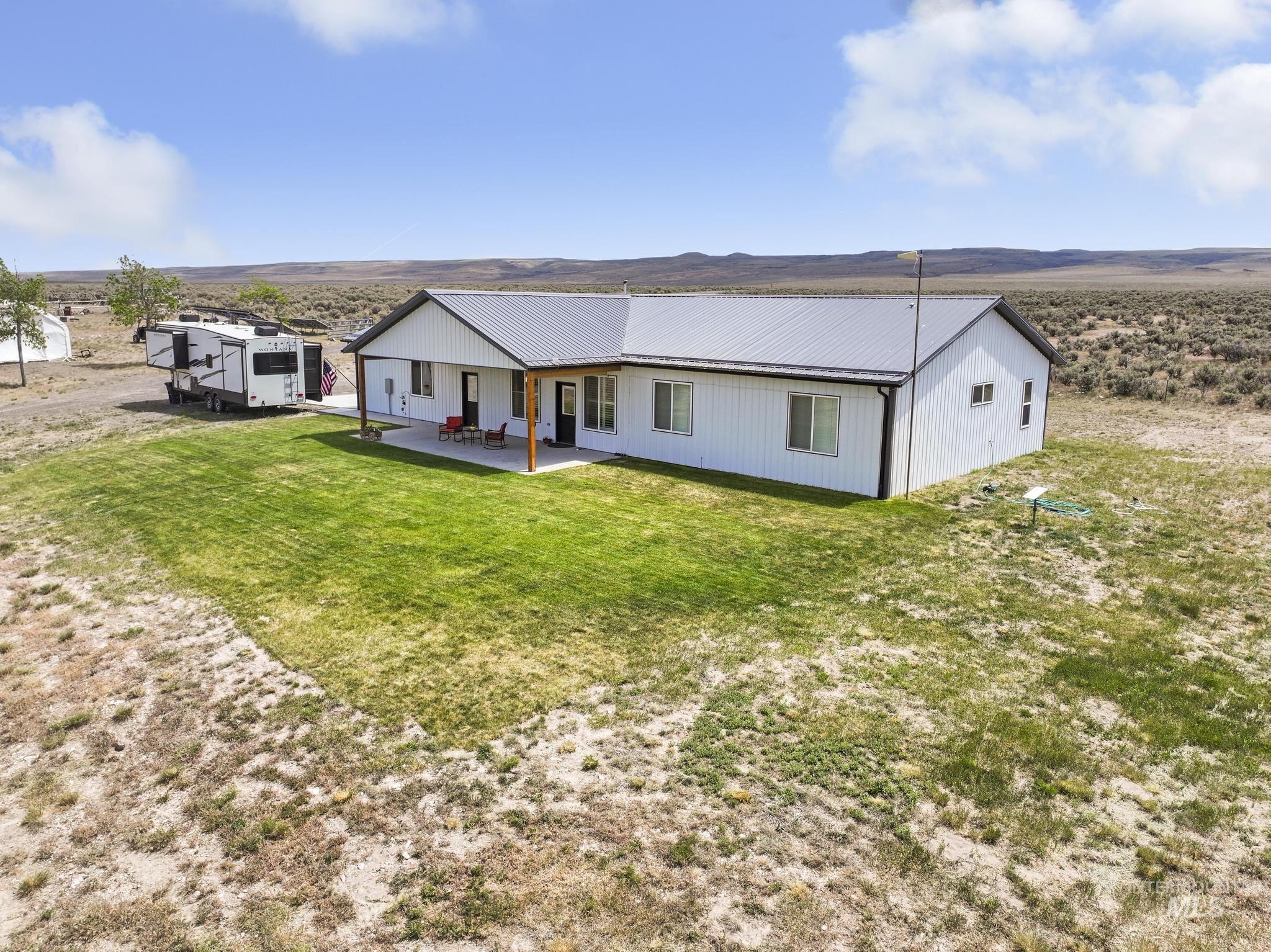 758 Cedar Crk Road Rogerson, ID 83302 - Photo 42 of 50 Modern white exterior with a dark gray metal roof, featuring a covered patio with wood support beams and a concrete surface