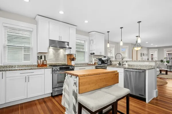 a kitchen with stainless steel appliances granite countertop a stove a sink dishwasher a stove and white cabinets next to a window