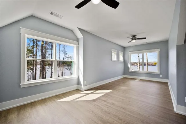 a view of an empty room with a window and wooden floor