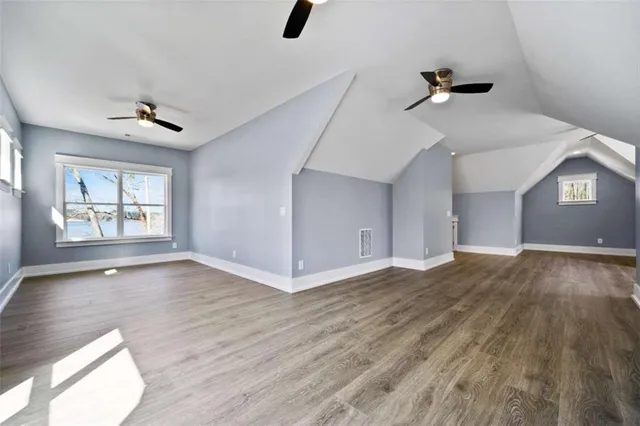 an empty room with wooden floor chandelier fan and windows