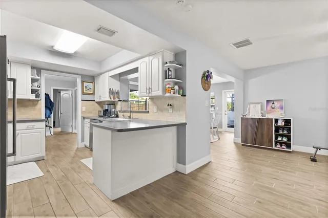 a large white kitchen with cabinets a sink and a refrigerator