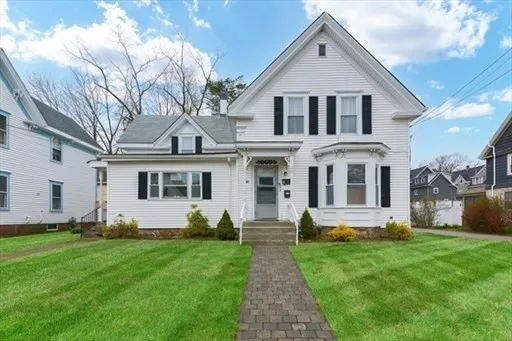 a front view of a house with a yard and potted plants