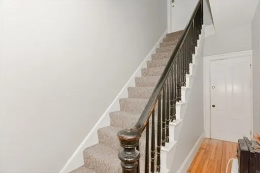 a view of staircase with wooden floor and white walls