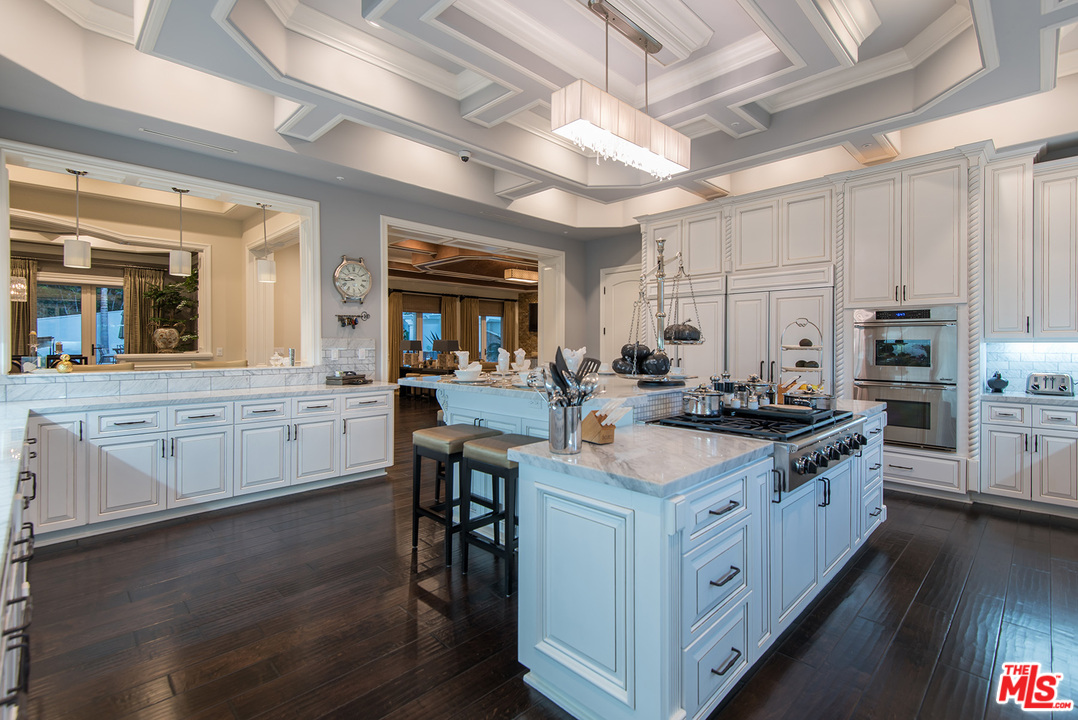 15506 Meadowgate Road Encino, CA 91436 - Photo 12 of 50 a kitchen with stainless steel appliances a sink stove and white cabinets with wooden floor