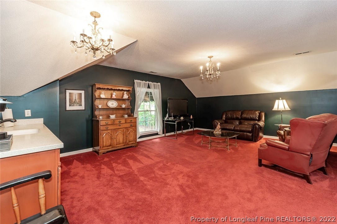 503 Queensferry Road Cary, NC 27511 - Photo 39 of 49 a living room with furniture a chandelier a fireplace and a flat screen tv