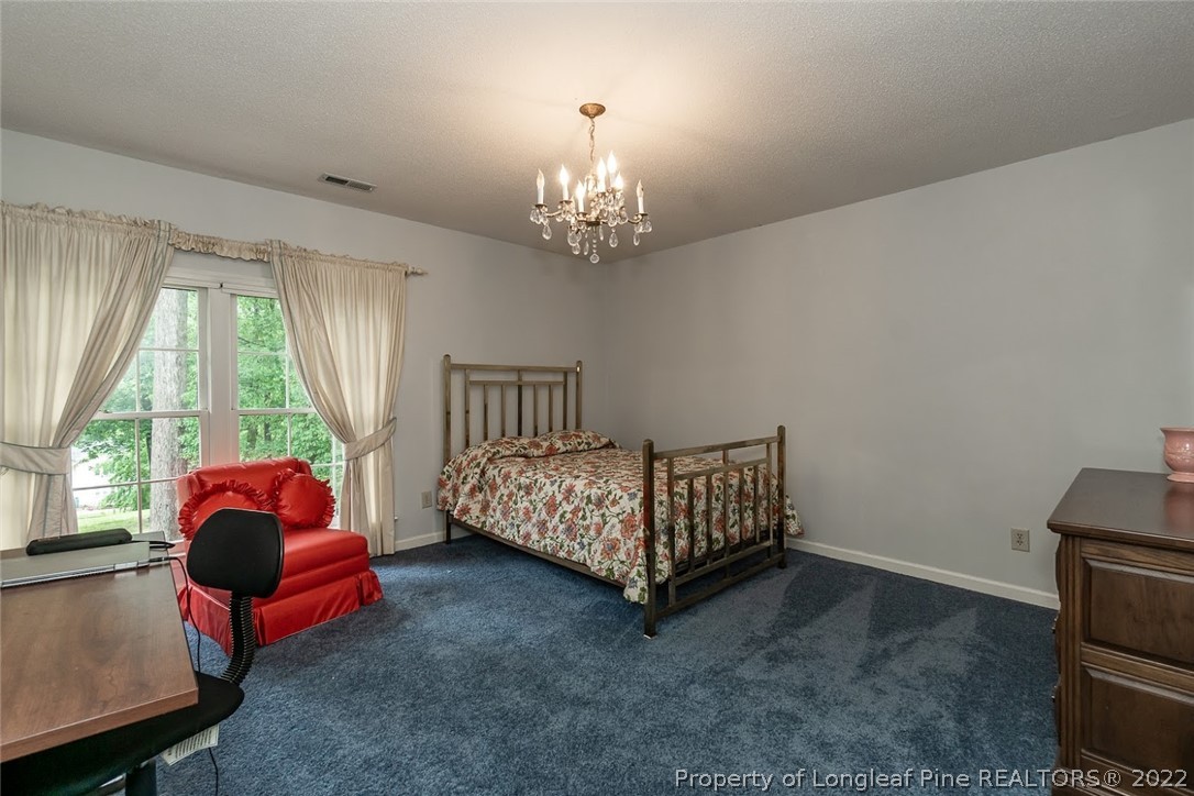 503 Queensferry Road Cary, NC 27511 - Photo 44 of 49 a bedroom with a bed and a chandelier