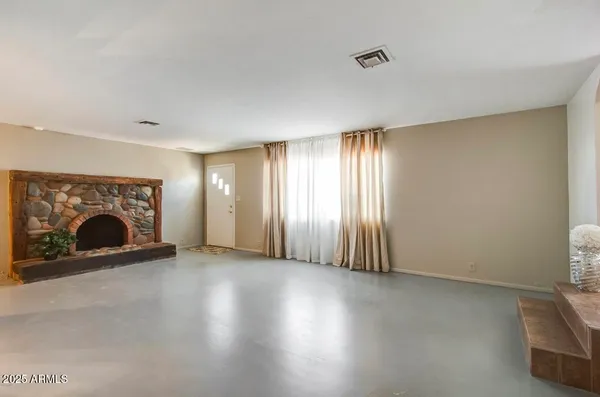 a view of an empty room with a fireplace and a window