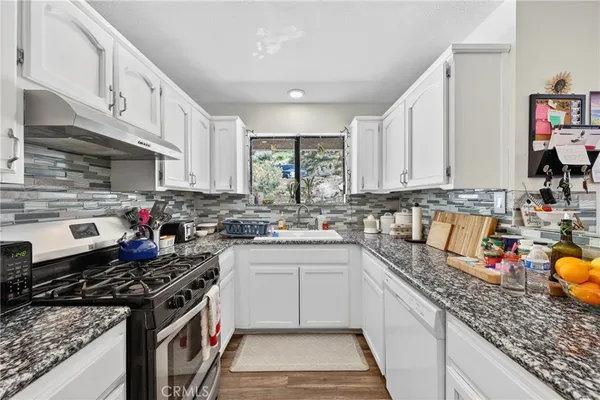 a kitchen with stainless steel appliances granite countertop a stove sink and cabinets