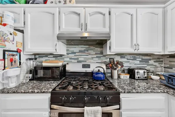 a kitchen with granite countertop a stove and white cabinets