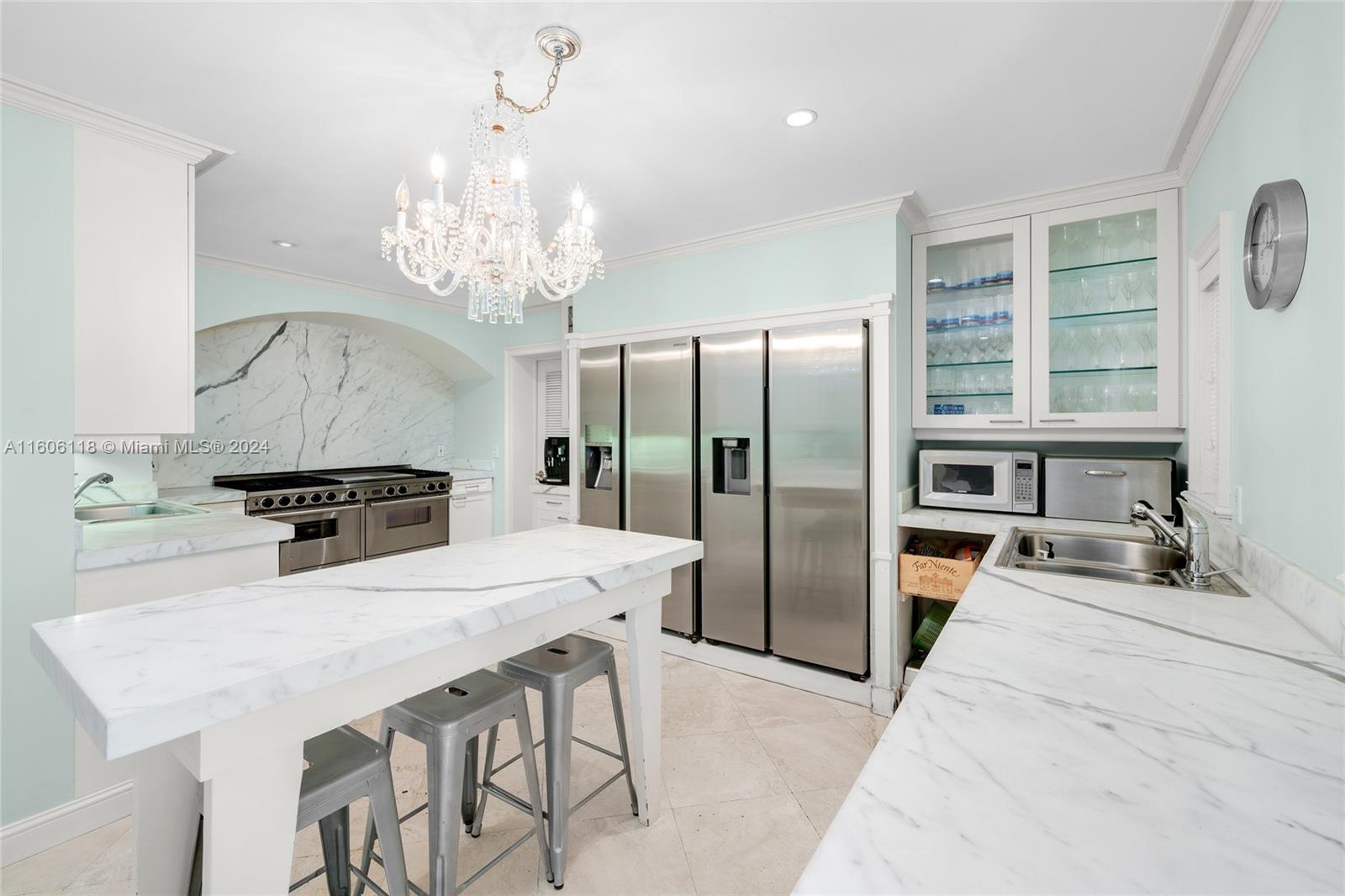 4810 North Bay Road Miami Beach, FL 33140 - Photo 33 of 61 a kitchen with stainless steel appliances a table and chairs