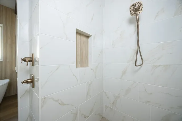 a bathroom with a white tub sink vanity granite and mirror
