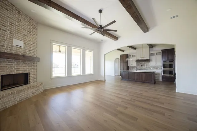 a view of empty room with fireplace and wooden floor
