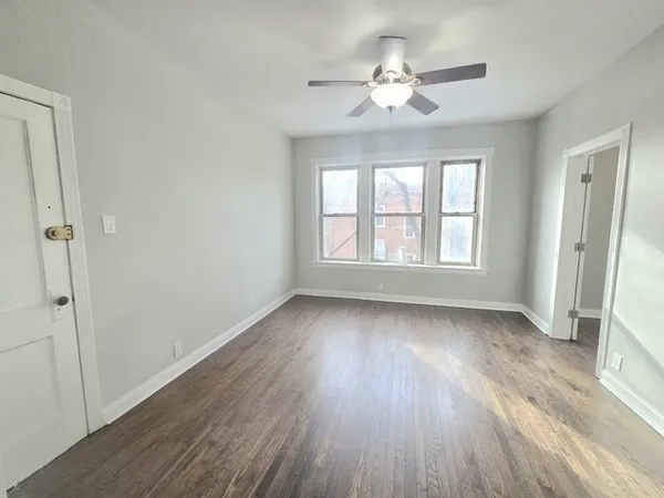 an empty room with wooden floor and fan