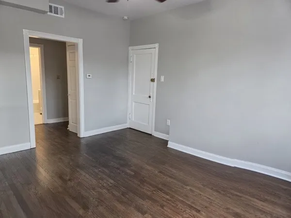 an empty room with wooden floor chandelier and windows