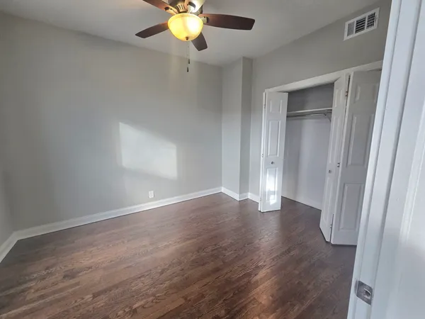a view of empty room with wooden floor and fan