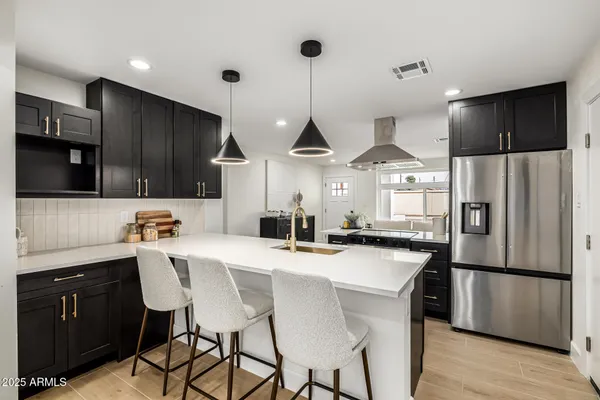 a kitchen with stainless steel appliances kitchen island granite countertop a refrigerator a sink dishwasher a stove and white countertops with wooden floor