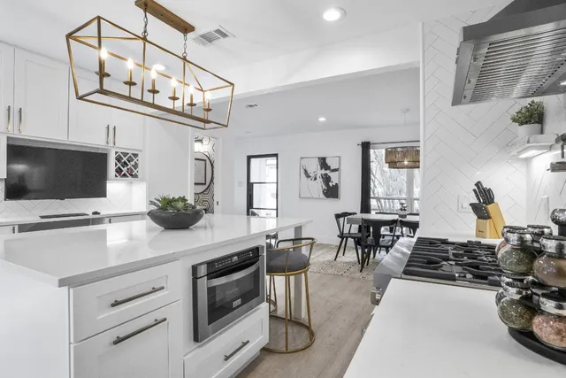 a kitchen with stainless steel appliances granite countertop a stove top oven a sink dishwasher a dining table and chairs with wooden floor