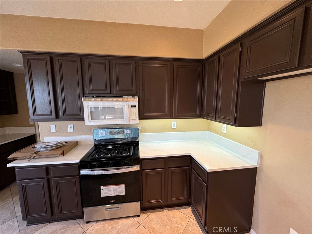 31970 Cercle Chambertin Temecula, CA 92591 - Photo 13 of 45 a kitchen with wooden cabinets a stove and a microwave