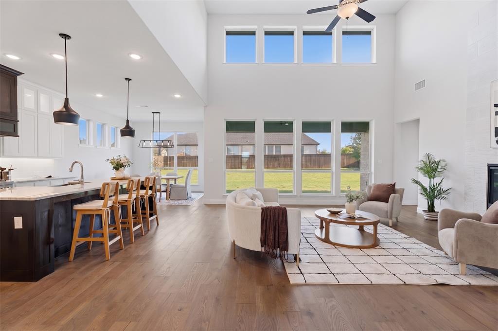 1316 Limestone Ridge Road Mansfield, TX 76063 - Photo 7 of 40 Open-concept living space featuring wood-finish flooring, a two-story ceiling, and a kitchen island with seating