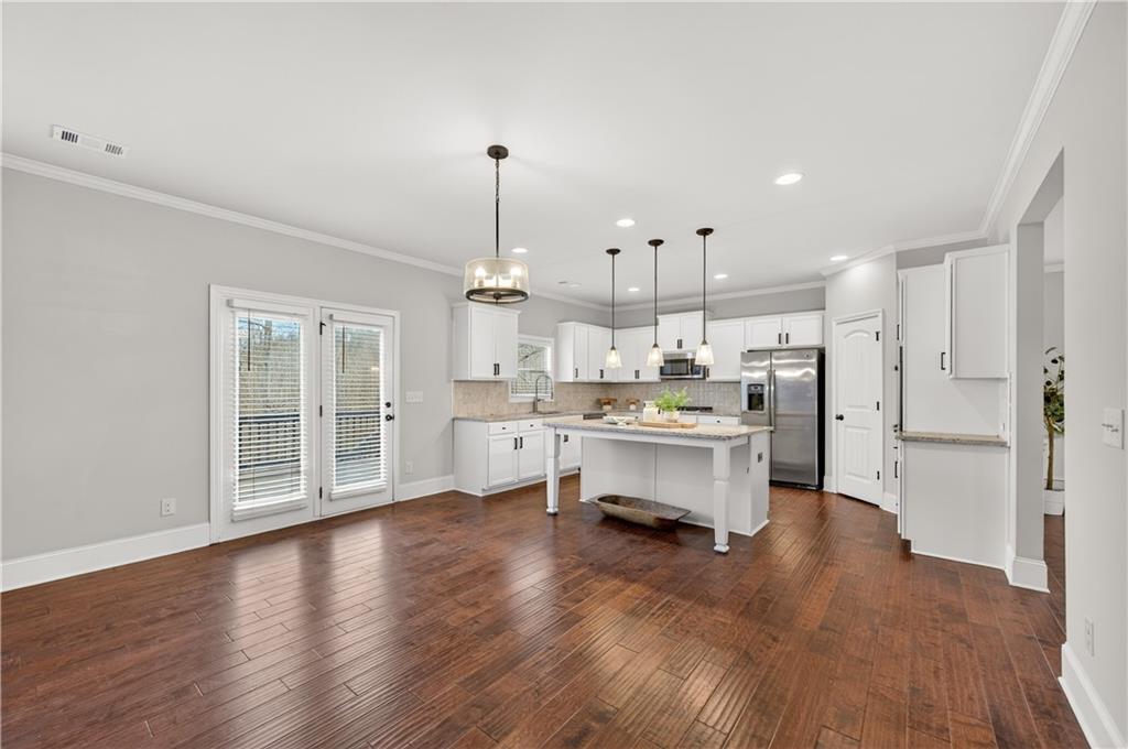 5875 Chestnut Drive Cumming, GA 30040 - Photo 21 of 55 a kitchen with stainless steel appliances kitchen island granite countertop a refrigerator a sink a stove and white cabinets with wooden floor