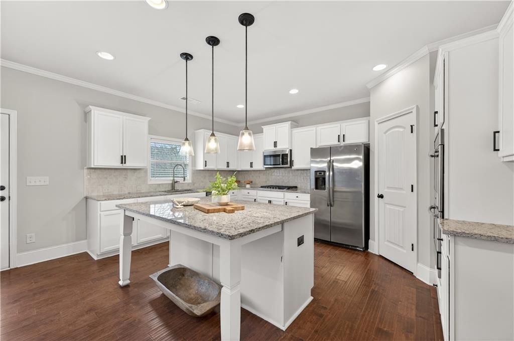 5875 Chestnut Drive Cumming, GA 30040 - Photo 22 of 55 a kitchen with stainless steel appliances kitchen island wooden floors and white cabinets