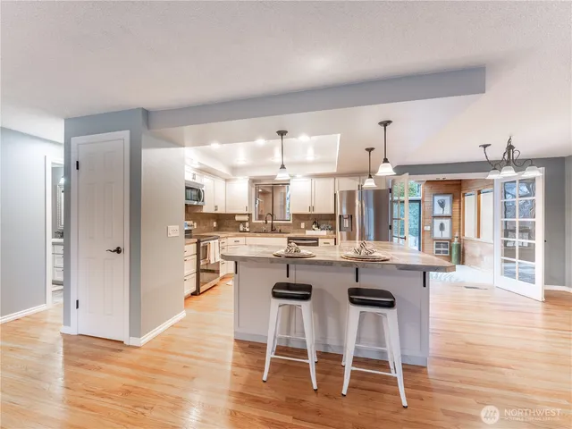 a dining hall with stainless steel appliances kitchen island granite countertop a dining table chairs and view living room