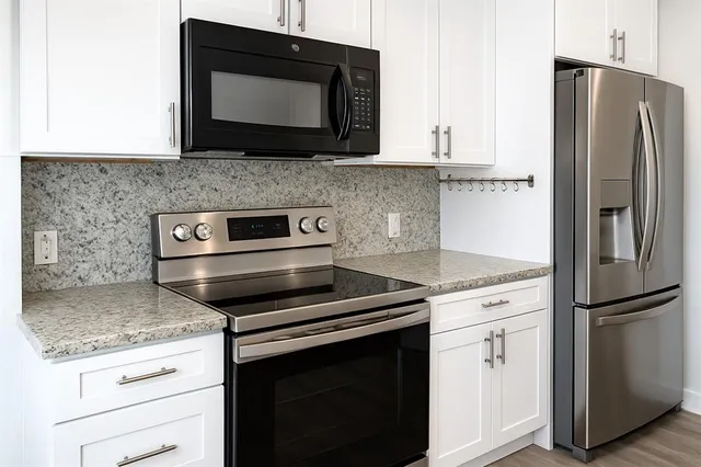 a kitchen with granite countertop a stove microwave and refrigerator