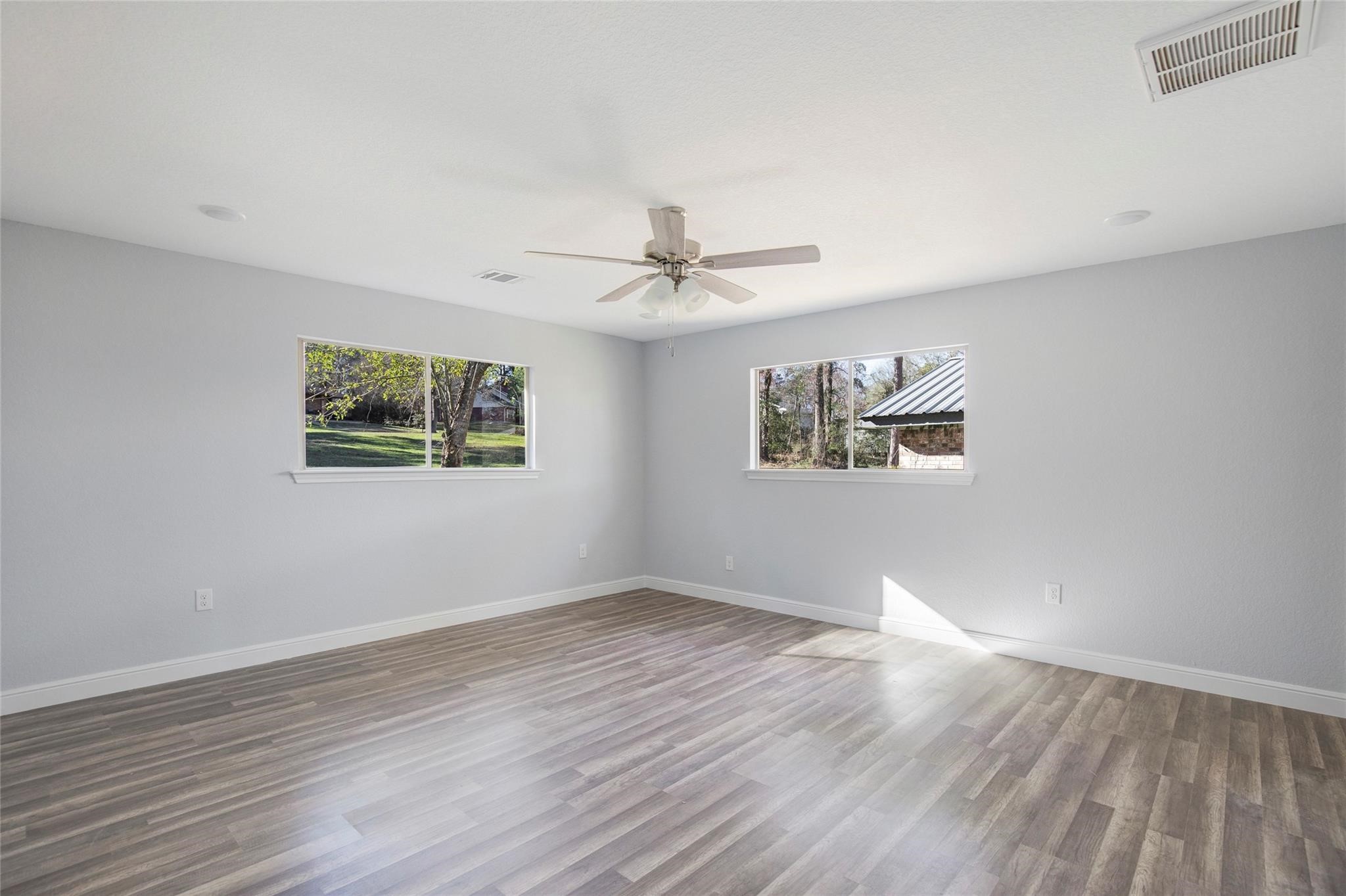 1 Mill Creek Road Point Blank, TX 77364 - Photo 21 of 43 an empty room with wooden floor ceiling fan and windows